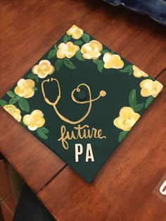 a green graduation cap with yellow flowers and a stethoscope on it that says future pa