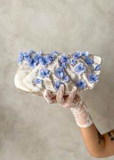 *Enjoy 10% off for a limited time. Use coupon code LIMITED10 at checkout. Does not include bespoke or custom changes. Utterly romantic and bursting with charm, the Isabella blue wedding clutch was inspired by the ethereal beauty of hydrangea flowers in full bloom. Each floral element is lovingly handcrafted, capturing the essence of nature's elegance with exquisite detail. The purse features a sculptural ruffle detail that frames the piece, reminiscent of the delicate folds found in a hydrangea Blue Wedding Clutch Evening Bag, Blue Clutch Evening Bag For Wedding, Blue Handmade Bags For Wedding, Blue Handmade Bag For Wedding, Handmade Blue Bag For Wedding, Blue Handmade Evening Bag For Wedding, Bride Clutch, Wedding Clutch Purse, Mother Of The Groom Gift