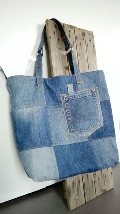 a bag made out of jeans hanging on a wooden wall next to a piece of wood