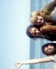 three women standing next to each other near the ocean