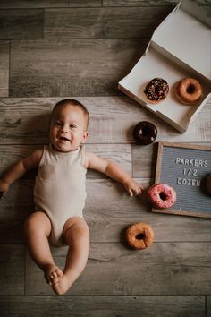 a baby laying on the floor next to doughnuts