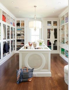 a large white kitchen with lots of shelves and drawers on the wall, along with an island in the middle