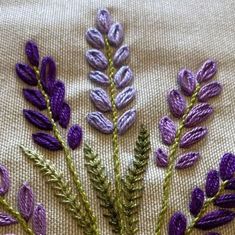 some purple flowers and green leaves on a white cloth