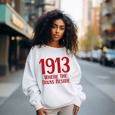 1913 Where the Divas Reside Unisex Sweatshirt The 1913 Where the Divas Reside Sweatshirt is a must-have for any Delta Sigma Theta Sorority member. The bold and striking design features the year of the sorority's founding, along with the phrase "Where the Divas Reside," making it the perfect way to show off your Delta pride. Whether you're running errands or attending a chapter meeting, this sweatshirt is sure to turn heads and make a statement. Don't miss out on this iconic piece of Delta Sigma Theta apparel! FIT and STYLING:  * Sweatshirt Composition: 50% Cotton / 50% Polyester, 8.0 oz. fabric weight  * Reduced pilling and softer air-jet spun yarn  * 1x1 athletic rib knit collar, cuffs, and waistband with spandex  * Double-needle stitched collar, shoulders, armholes, cuffs, and waistband, Theta Sweatshirt, Delta Sigma Theta Apparel, Theta Sorority, Delta Sigma Theta Sorority, Costume National, Jumpsuit Men, Delta Sigma Theta, Urban Outfits, Men's Coats And Jackets