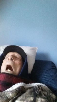 a man laying in bed with his mouth open