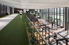 an indoor gym with rows of treadmills and large windows overlooking the green grass