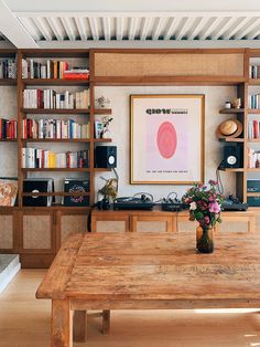 a wooden table sitting in front of a book shelf filled with books