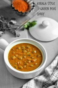 a white bowl filled with green pea curry next to a spoon and some other items