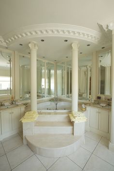 a large white bathroom with columns and sinks