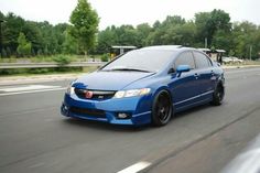 a blue honda civic is driving down the road