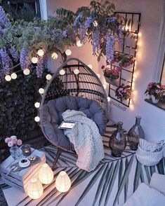 an outdoor area with lights and wicker furniture on the ground next to potted plants