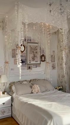 a white bed sitting under a chandelier in a bedroom next to a dresser