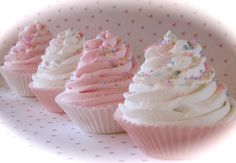 three cupcakes with white frosting and sprinkles are on a plate