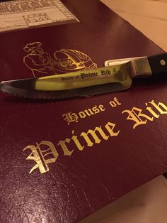 a close up of a red book with a knife on it and the words house of prime bid