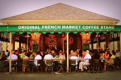 a group of people sitting at tables in front of a french market with green awnings