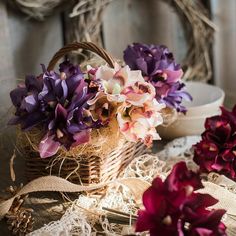 purple and white flowers in a basket next to lace doily on a wooden table