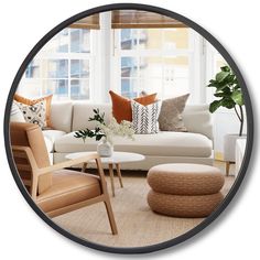 a living room with white couches and orange pillows on the windowsill, surrounded by large round mirrors