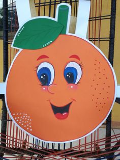 an orange with a green leaf on it's head is sitting in a cage