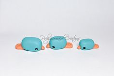 three small blue birds with orange feet on a white surface