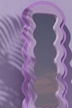 a mirror that is sitting on the wall next to a purple wall with a shadow cast on it