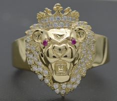 Our Real 10K Solid Yellow Gold 17mm CZ Red Eye Medium Shiny Lion Head Ring is an exquisite piece of artistry. Crafted of highly polished 10K gold, it features an ornately detailed 17mm lion head, complete with a sparkling pair of cubic zirconia red eyes. The piece weighs an impressive 4.8 grams and is sure to make an impactful and regal statement. Perfect for the lionhearted among us!  Specifications: Metal: Real 10K Yellow Gold (Stamped, 10K) Condition: Brand New Polished: Shiny Gold Weight 4.8 Luxury Yellow Gold Crown Shaped Jewelry, Luxury Yellow Gold Crown Design Rings, Lion Jewelry Woman, Gold Lion Ring, Lion Pendant Gold, Unique Gold Rings, 10k Gold Ring, Head Ring, Lion Head