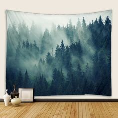 a forest tapestry hanging on the wall in front of a vase and other decor items