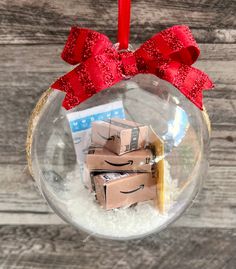 a glass ornament filled with boxes and a red ribbon