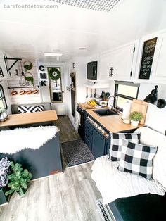 the interior of an rv with wood flooring and white walls, black appliances and decor