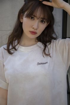 a young woman is holding her hair in front of her head and looking at the camera