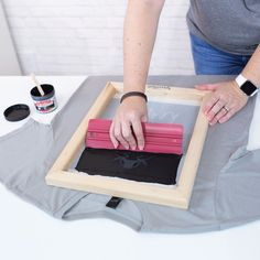 a woman is making an art project with red and black paint on the canvass