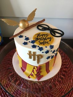 a harry potter themed birthday cake on a glass plate with a gold spoon and wand