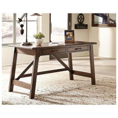 a wooden desk sitting on top of a carpeted floor next to a large window