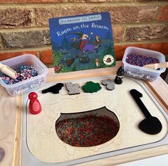 a wooden table topped with lots of crafting supplies next to a children's book