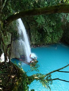 people are swimming in the blue water near a waterfall with a man made waterfall coming out of it