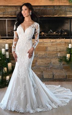 a woman in a white wedding dress standing next to a fireplace with candles on it