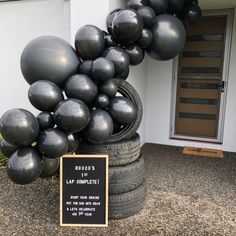 a bunch of black balloons sitting on top of a pile of tires next to a sign