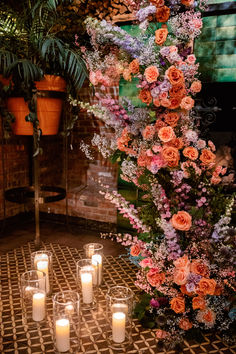 many candles are lit on the floor in front of flowers