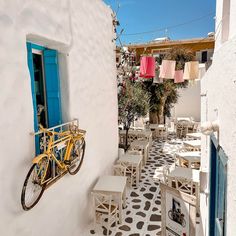 an alleyway with tables, chairs and a yellow bicycle hanging from the side wall