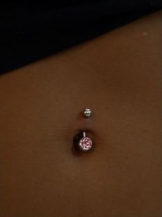 a woman's belly with two piercings on it and one pink diamond in the middle