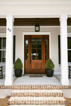 two potted plants sit on the front steps of a house