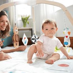 two women and a baby are playing with toys on the bed in their room,