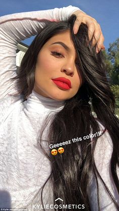 a woman with long black hair and red lipstick is posing for the camera while wearing a white shirt