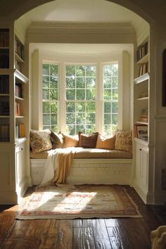 the sun shines through an arched window into a room with bookshelves and windows