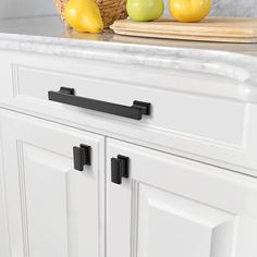 a kitchen with white cabinets and black handles