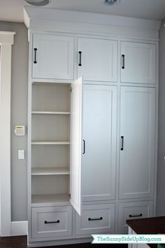 an empty room with white cabinets and drawers