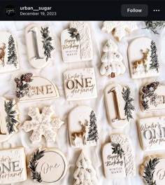 christmas cookies are arranged on a white tablecloth with evergreens and snowflakes