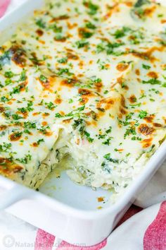 a casserole dish with cheese and spinach in it on a red and white cloth