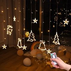 a person holding a remote control in front of some christmas decorations and lights hanging from the ceiling