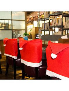 three red santa hats sitting on top of chairs in front of a book shelf filled with books