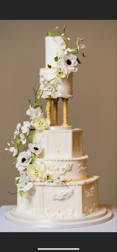 a wedding cake with white flowers and gold decorations on it's tiered tower